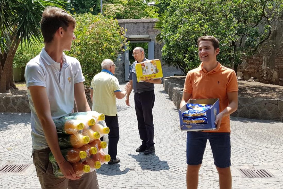 Due ragazzi aiutano un parroco gesuita a scaricare viveri per i poveri